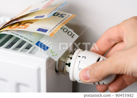 Hand adjusting the valve knob of heating radiator temperature thermostat with of euro money 90455982