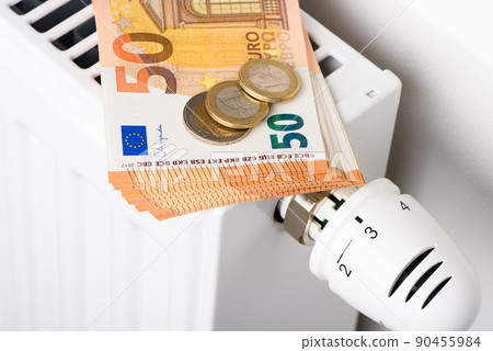 50 euro banknotes and coins on heating radiator battery with thermostat temperature regulator. 50 euro banknotes and coins on heating radiator battery with thermostat temperature regulator. 90455984