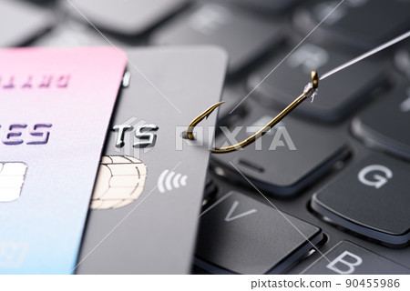 Credit card on fishing hook pulled from stack on keyboard, phishing scam data theft concept 90455986