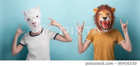 Woman in lion and alpaca mask with hands in rock metal sign, isolated on blue background 90456330