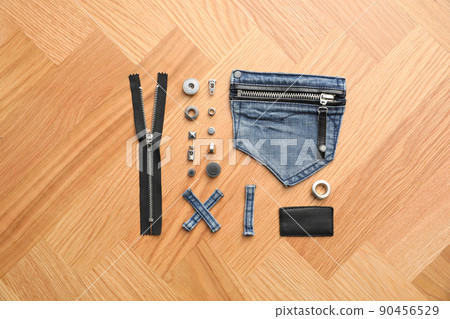Flat lay composition with garment accessories and cutting details for jeans on table Flat lay composition with garment accessories and cutting details for jeans on table 90456529
