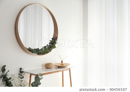 Round mirror with wooden frame in light room Round mirror with wooden frame in light room 90456587