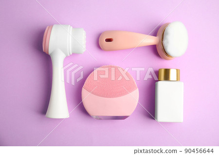 Flat lay composition with face cleansing brushes on violet background. Cosmetic tools 90456644