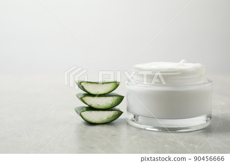 Open jar of cream and cut aloe on grey table. Organic cosmetics 90456666