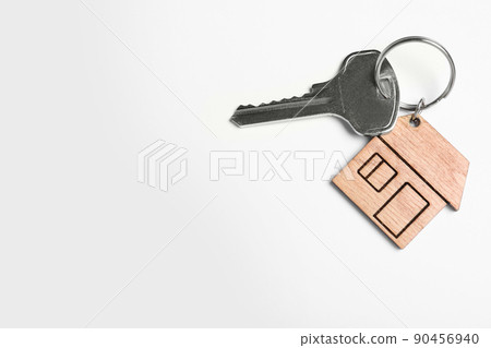 Key with trinket in shape of house isolated on white, top view. Real estate agent services 90456940