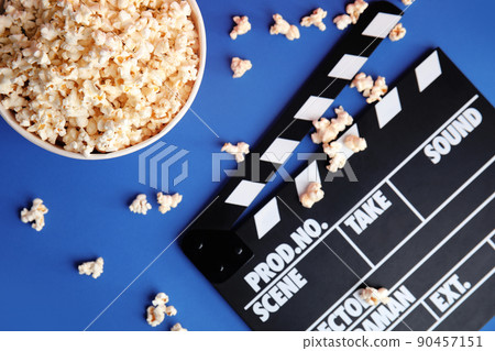 Tasty pop corn and clapboard on blue background, flat lay 90457151