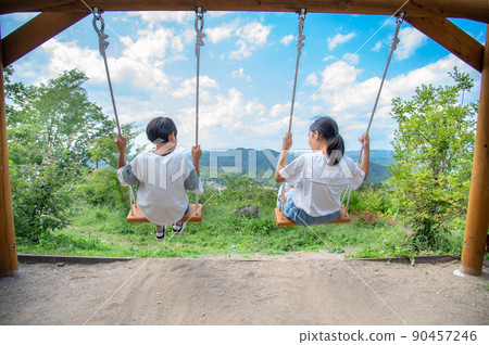 Asian elementary school students playing on a wooden swing on the top of a mountain Asian elementary school students playing on a wooden swing on the top of a mountain 90457246
