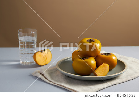 Front view of a glass of persimmon in brown background for food advertisement Front view of a glass of persimmon in brown background for food advertisement 90457555