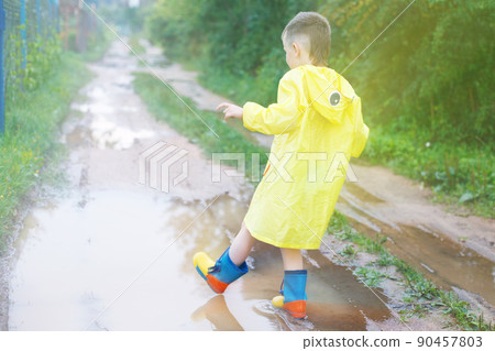 child's feet in a rubber boot in a puddle 90457803