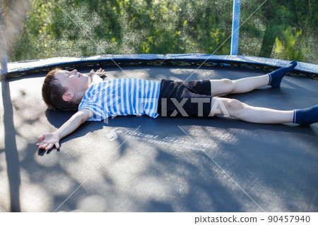 boy on  the trampoline. the child lies on a trampoline and rests 90457940