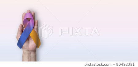 Bladder cancer awareness ribbon with marigold purple blue bow on hand support on color background with copy space 90458381