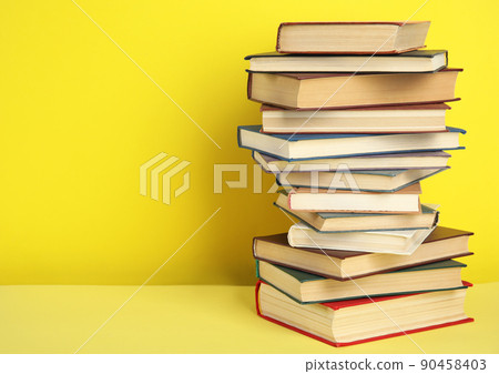 Stack of hardcover books on yellow background. Space for text 90458403
