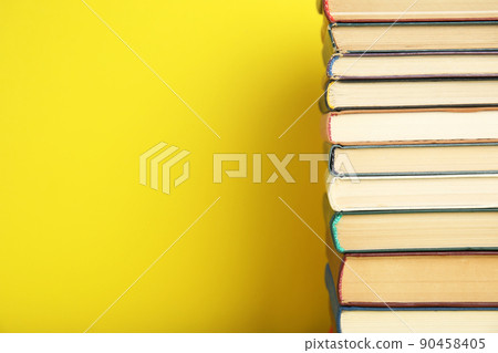 Stack of hardcover books on yellow background. Space for text 90458405
