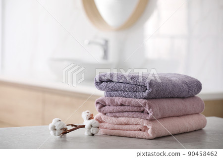 Stack of fresh towels and cotton flowers on table in bathroom 90458462