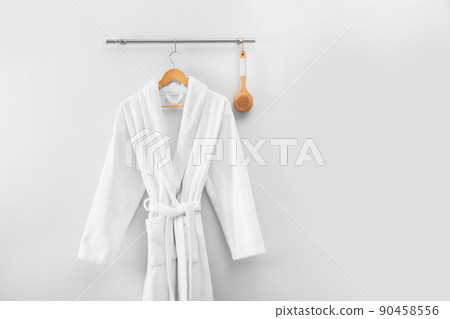 Hanger with clean bathrobe and brush on light wall. Space for text Hanger with clean bathrobe and brush on light wall. Space for text 90458556