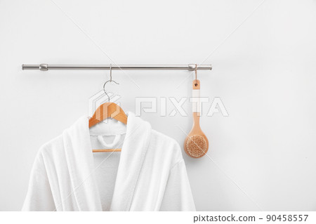 Hanger with clean bathrobe and brush on light wall Hanger with clean bathrobe and brush on light wall 90458557
