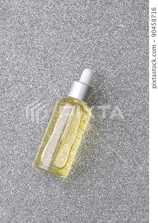 Yellow vitamin C yellow serum in transparent bottle on sparkling silver grey background. Beauty and health concept. Mockup for your design with copy space. Flat lay style. 90458716