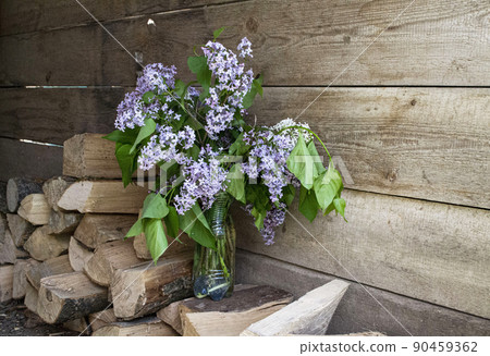 A bouquet of lilacs on the background of wooden boards and firewood. A bouquet of lilacs on the background of wooden boards and firewood. 90459362