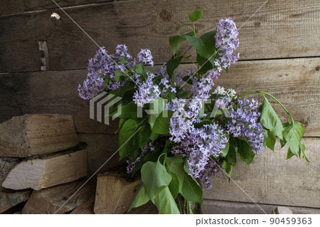 A bouquet of lilacs on the background of wooden boards and firewood.  90459363