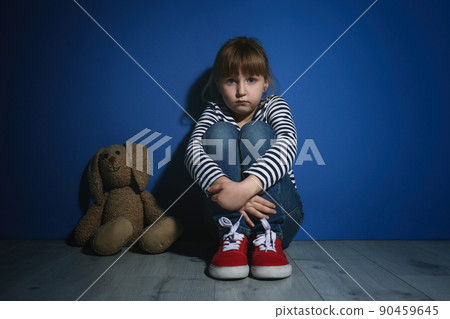 Abused little girl with toy near blue wall. Domestic violence concept 90459645
