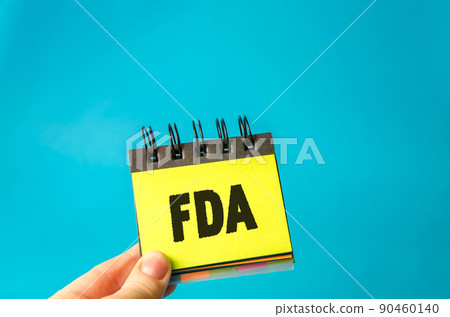 Sticky note in hands with the word FDA - Food and Drug Administration. Concept of promoting public health through the control and supervision of food safety, tobacco products. Sticky note in hands with the word FDA - Food and Drug Administration. Concept of promoting public health through the control and supervision of food safety, tobacco products. 90460140