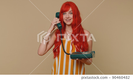 Cheerful red hair girl secretary talking on wired vintage telephone of 80s, say hey you call me back Cheerful red hair girl secretary talking on wired vintage telephone of 80s, say hey you call me back 90460482