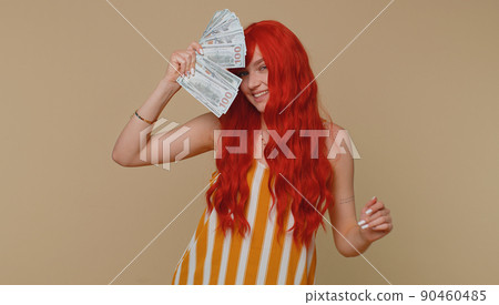 Redhead girl holding cash money dollar celebrate dance, success business career, lottery game winner Redhead girl holding cash money dollar celebrate dance, success business career, lottery game winner 90460485