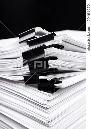 A stack of office papers, some of which are fastened with black binders A stack of office papers, some of which are fastened with black binders 90461970