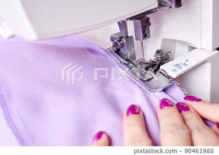Woman overstitches a dress on an overlocker 90461988