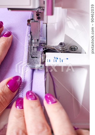 Woman overstitches a dress on an overlocker Woman overstitches a dress on an overlocker 90462039
