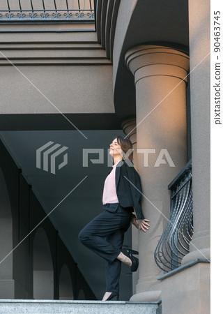Modern successful woman. Yong woman in suit and heels leaned against the wall. Full-length portrait Modern successful woman. Yong woman in suit and heels leaned against the wall. Full-length portrait 90463745