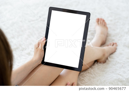 Online courses. Digital mockup. Virtual connection. Unrecognizable woman looking tablet computer blank screen sitting bed in light room interior. 90465677