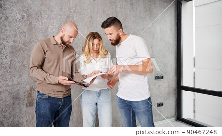 Man and woman looking at catalogue while choosing interior design for new apartment with professional designer. Couple planning home renovation and redesigning with specialist. Man and woman looking at catalogue while choosing interior design for new apartment with professional designer. Couple planning home renovation and redesigning with specialist. 90467248