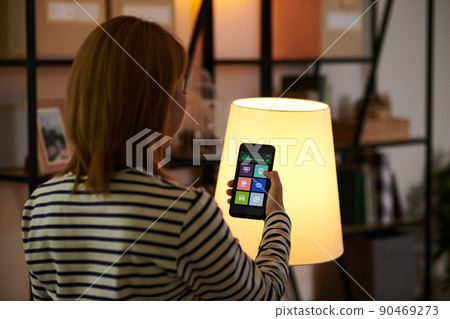 Woman Dimming Lights in Room 90469273