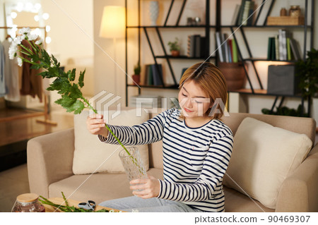 Woman Putting Leafy Stems in Vase Woman Putting Leafy Stems in Vase 90469307