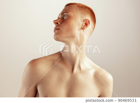 Portrait of young red-haired man posing shirtless, looking away isolated over grey studio background Portrait of young red-haired man posing shirtless, looking away isolated over grey studio background 90469531