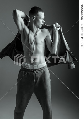 Portrait of stylish muscular young man posing, putting shirt over shoulders. Black and white photography. Male fashion 90469590