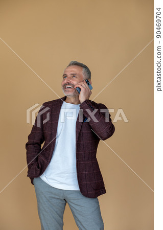 Man in a jacket talking on the phone and looking contented Man in a jacket talking on the phone and looking contented 90469704