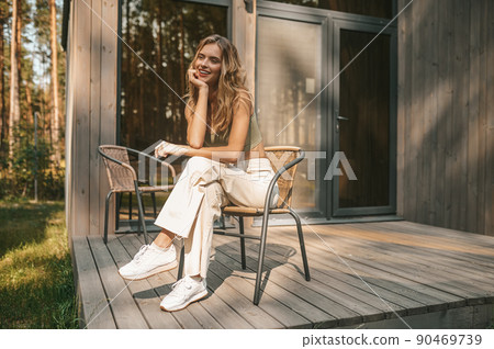 Pretty lady resting in the armchair on the wooden porch Pretty lady resting in the armchair on the wooden porch 90469739