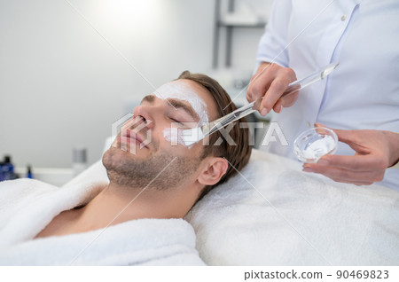 Cosmetologist applying cream on clients face with a brush 90469823