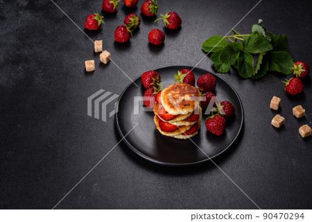 Cottage cheese pancakes with sliced strawberries and strawberry jam on a plate on a concrete background Cottage cheese pancakes with sliced strawberries and strawberry jam on a plate on a concrete background 90470294