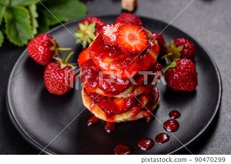 Cottage cheese pancakes with sliced strawberries and strawberry jam on a plate on a concrete background Cottage cheese pancakes with sliced strawberries and strawberry jam on a plate on a concrete background 90470299
