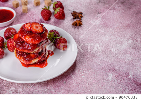 Cottage cheese pancakes with sliced strawberries and strawberry jam on a plate on a concrete background Cottage cheese pancakes with sliced strawberries and strawberry jam on a plate on a concrete background 90470335