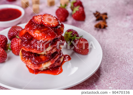 Cottage cheese pancakes with sliced strawberries and strawberry jam on a plate on a concrete background Cottage cheese pancakes with sliced strawberries and strawberry jam on a plate on a concrete background 90470336