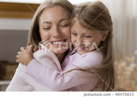 Loving little daughter cuddling her young mother, close up 90470815