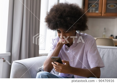Happy teenage Black student guy typing message on smartphone 90470916