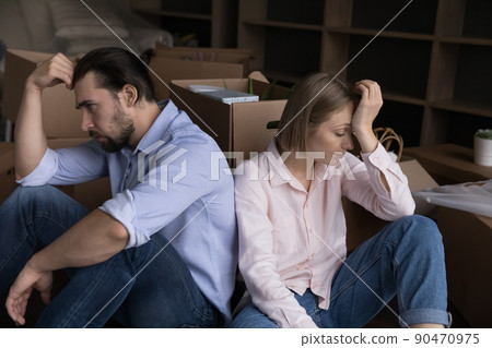 Unhappy tired couple sit on floor near boxes with stuff Unhappy tired couple sit on floor near boxes with stuff 90470975