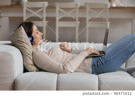 Happy 20s student girl in headphones watching learning webinar 90471012