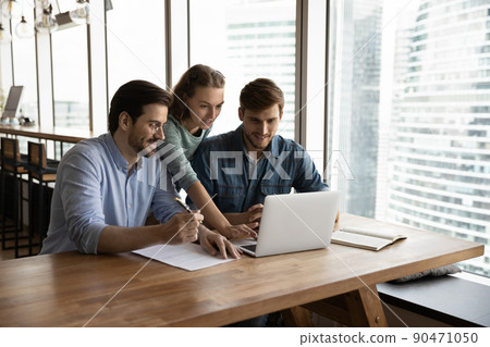 Creative business team sharing laptop in office 90471050