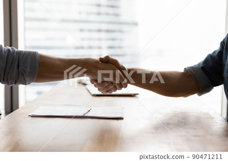 Two businessmen shaking hands over conference table in office Two businessmen shaking hands over conference table in office 90471211